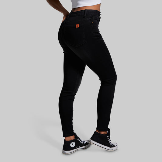 Person wearing black jeans and black sneakers on a gray background