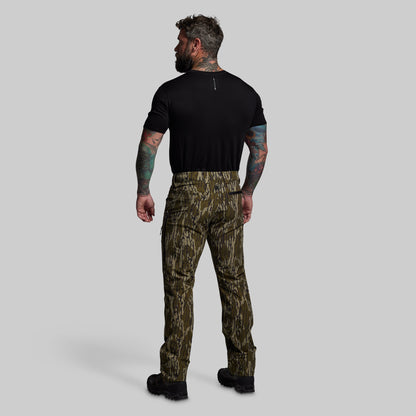 Man wearing camouflage pants and a black shirt on a gray background