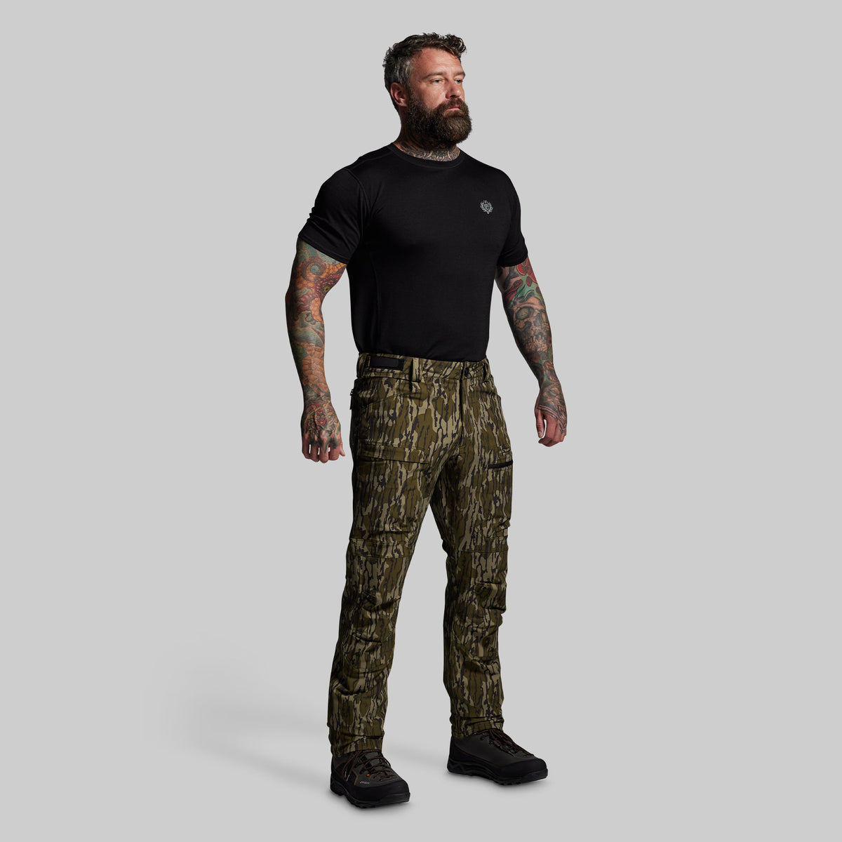Man wearing a black t-shirt and camouflage pants on a gray background