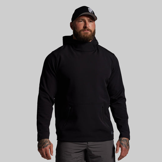 Man wearing a black hoodie and cap on a gray background