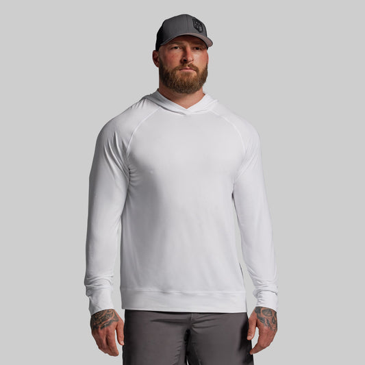 Man wearing a white long-sleeve shirt and gray cap on a gray background