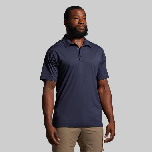 Man wearing a navy blue polo shirt against a gray background