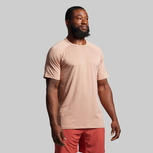 Man wearing a beige t-shirt and red pants against a gray background