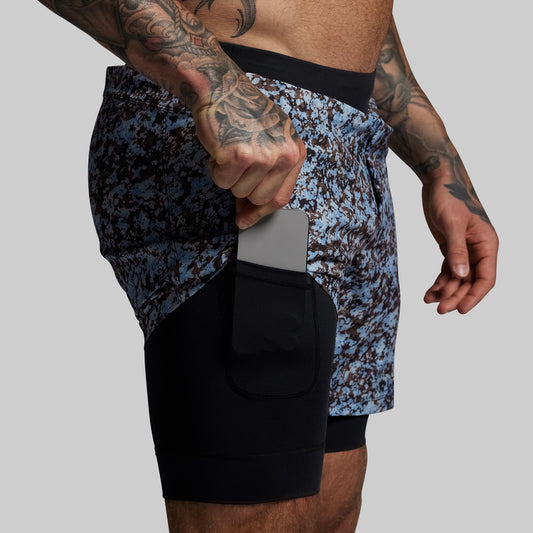Person wearing patterned athletic shorts with a black liner on a gray background