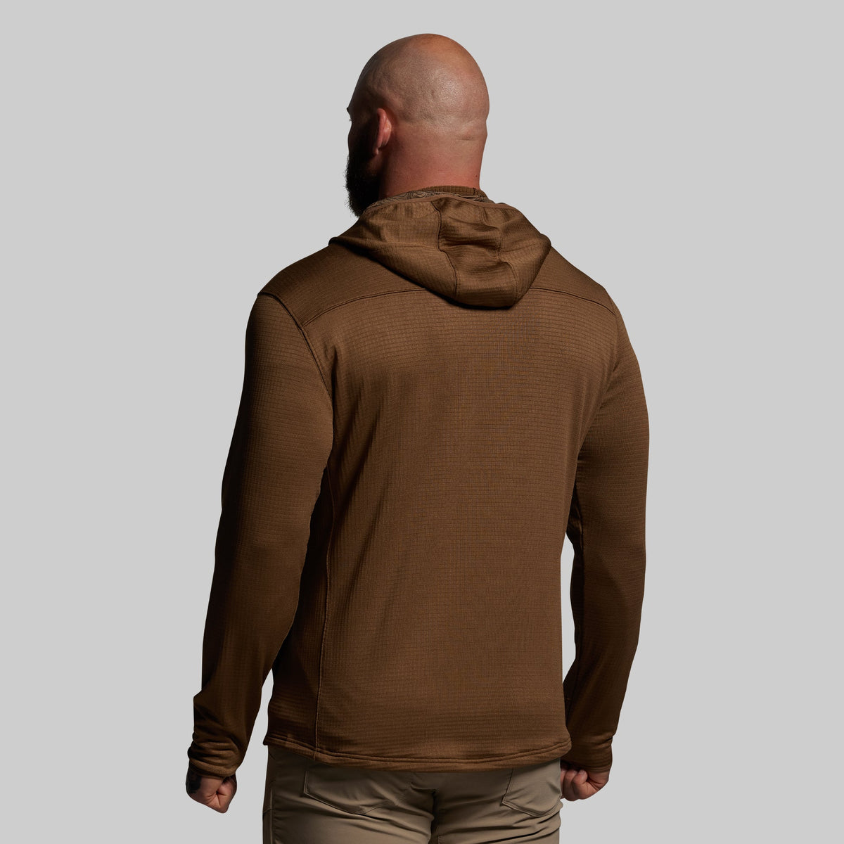 Man wearing a brown hoodie from behind on a gray background