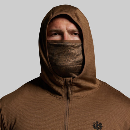 Person wearing a brown hoodie with a face covering on a gray background