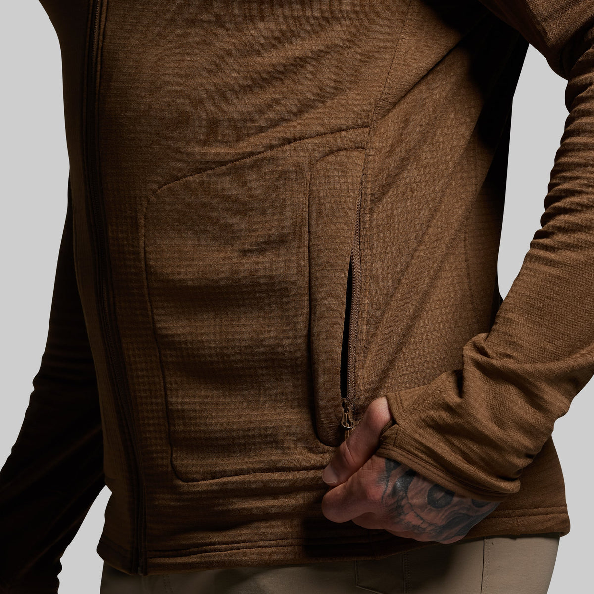 Brown hoodie with a focus on the pocket area against a neutral background