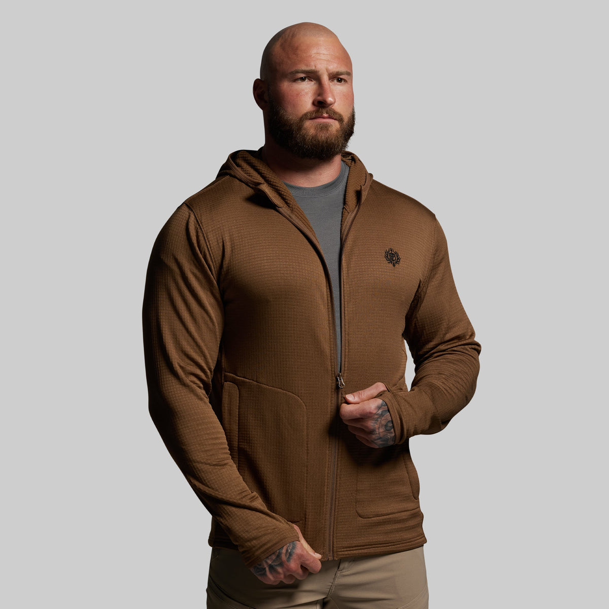 Man wearing a brown hoodie on a gray background