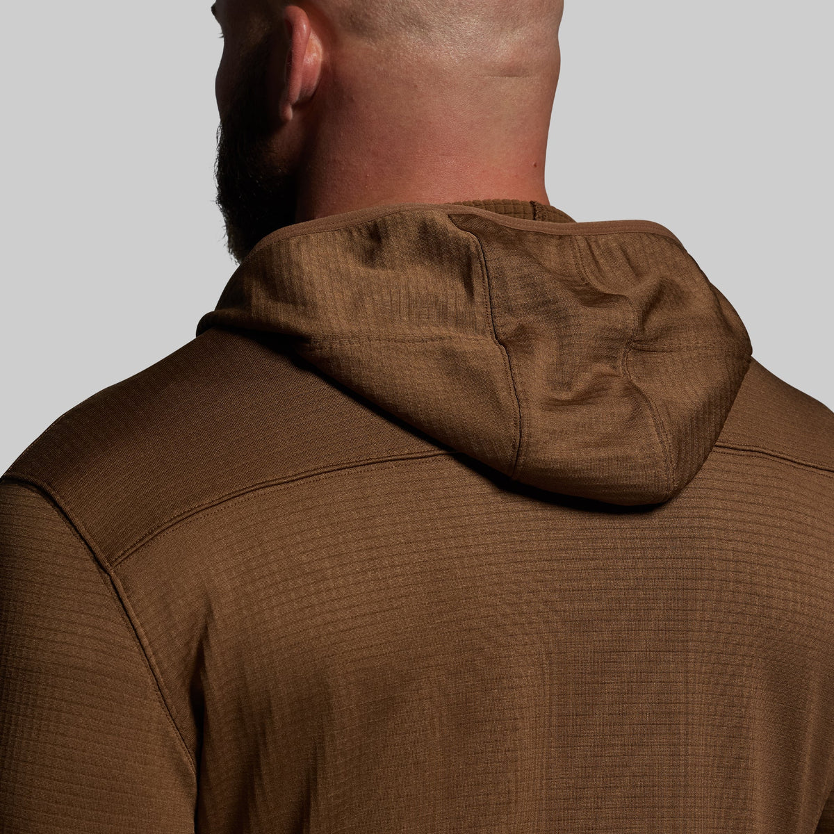 Brown hoodie worn by a person on a plain background