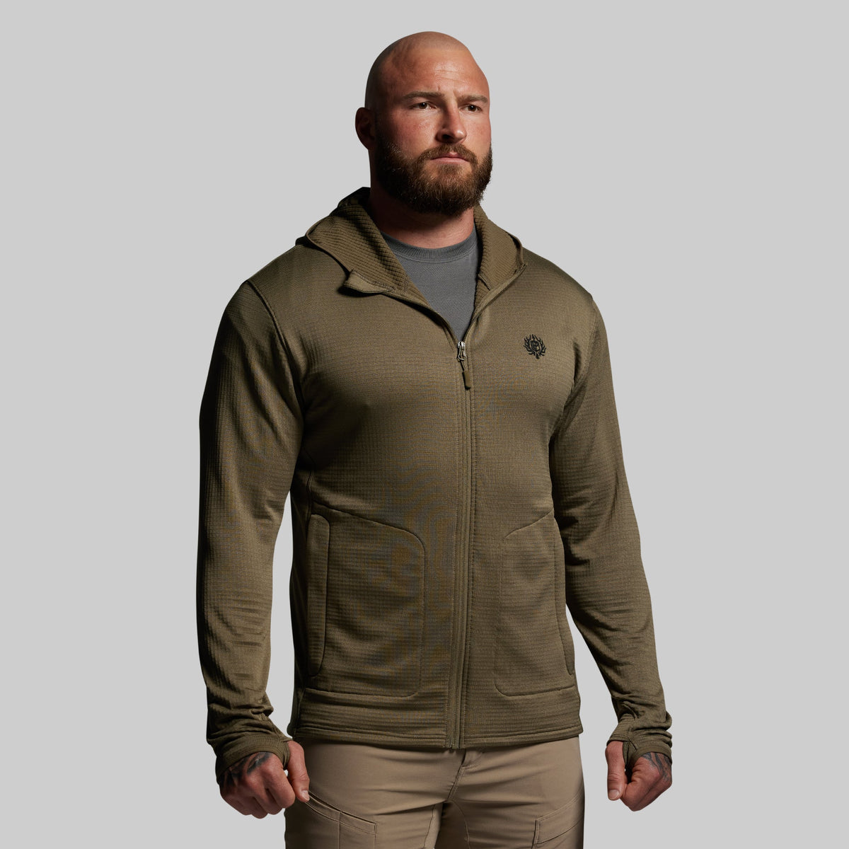 Man wearing a green full zip hoodie with a logo on a gray background