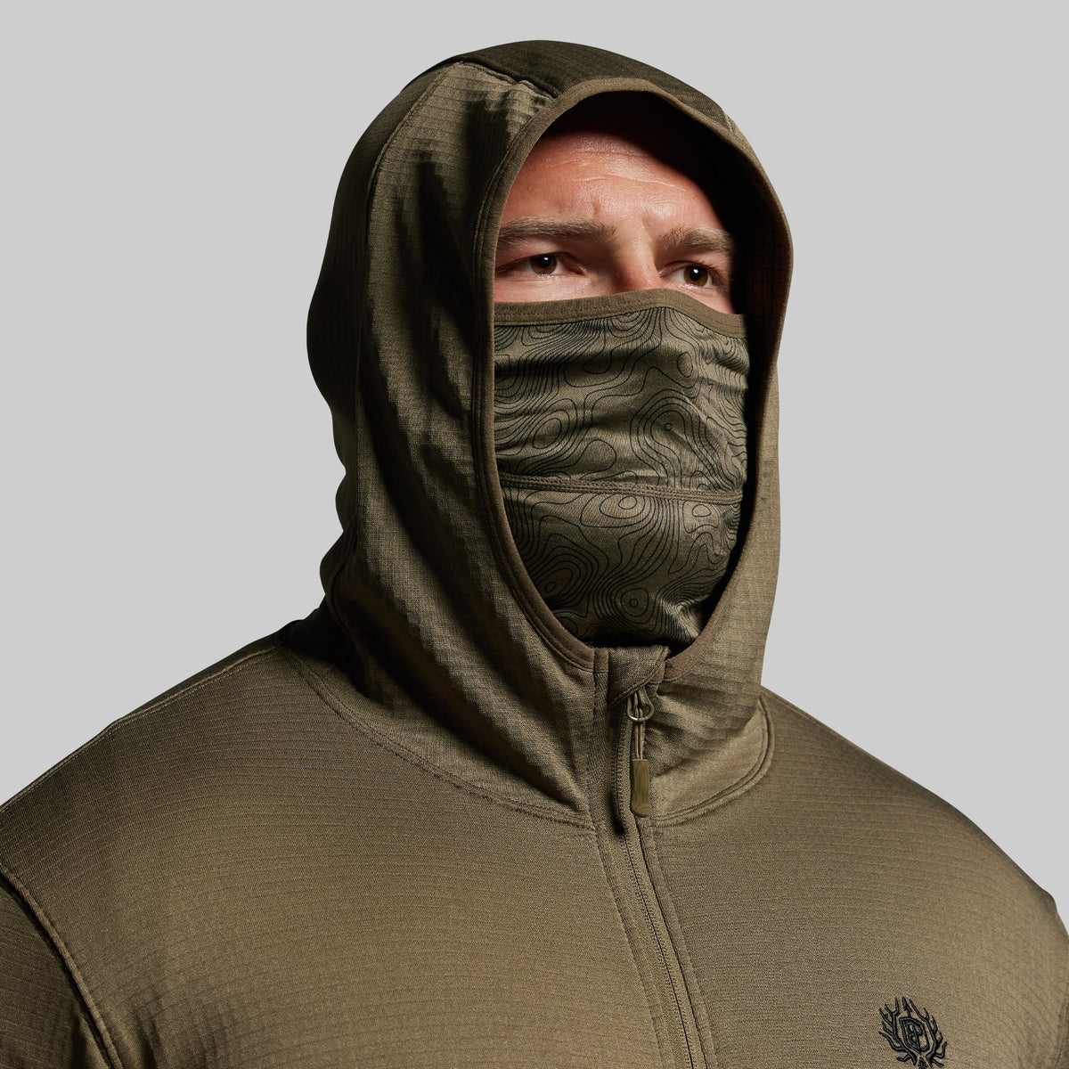 Person wearing a green hoodie with a face mask on a gray background