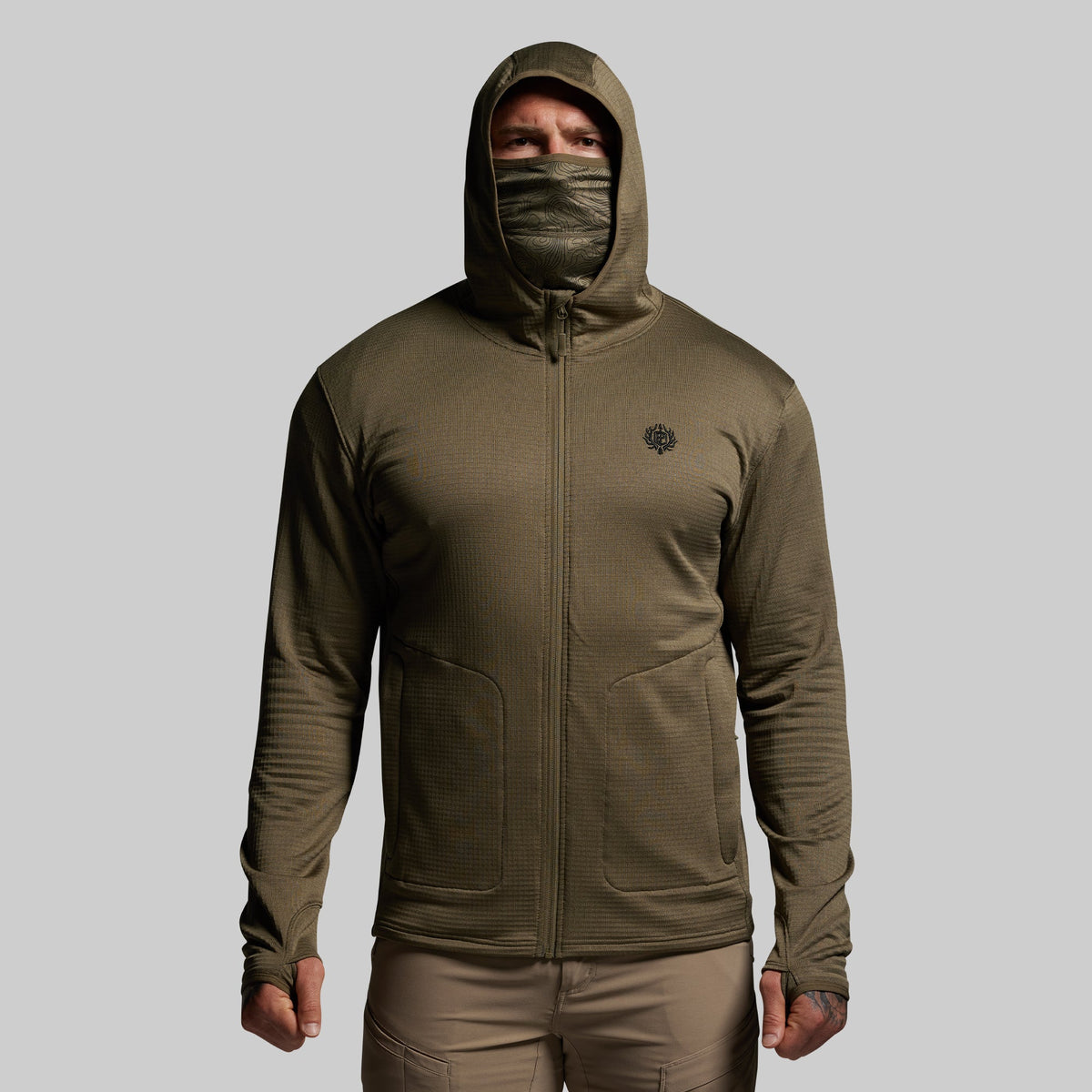 Person wearing a green hooded full zip mid layer on a gray background