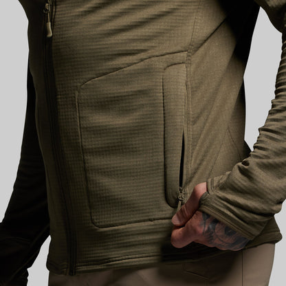 Close-up of a person wearing a green full zip hoodie with a pocket on a gray background