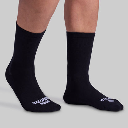 A pair of black crew socks with the brand name visible on the foot area, displayed on a person's legs.