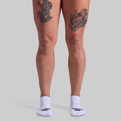 Person wearing white socks with text on a plain background