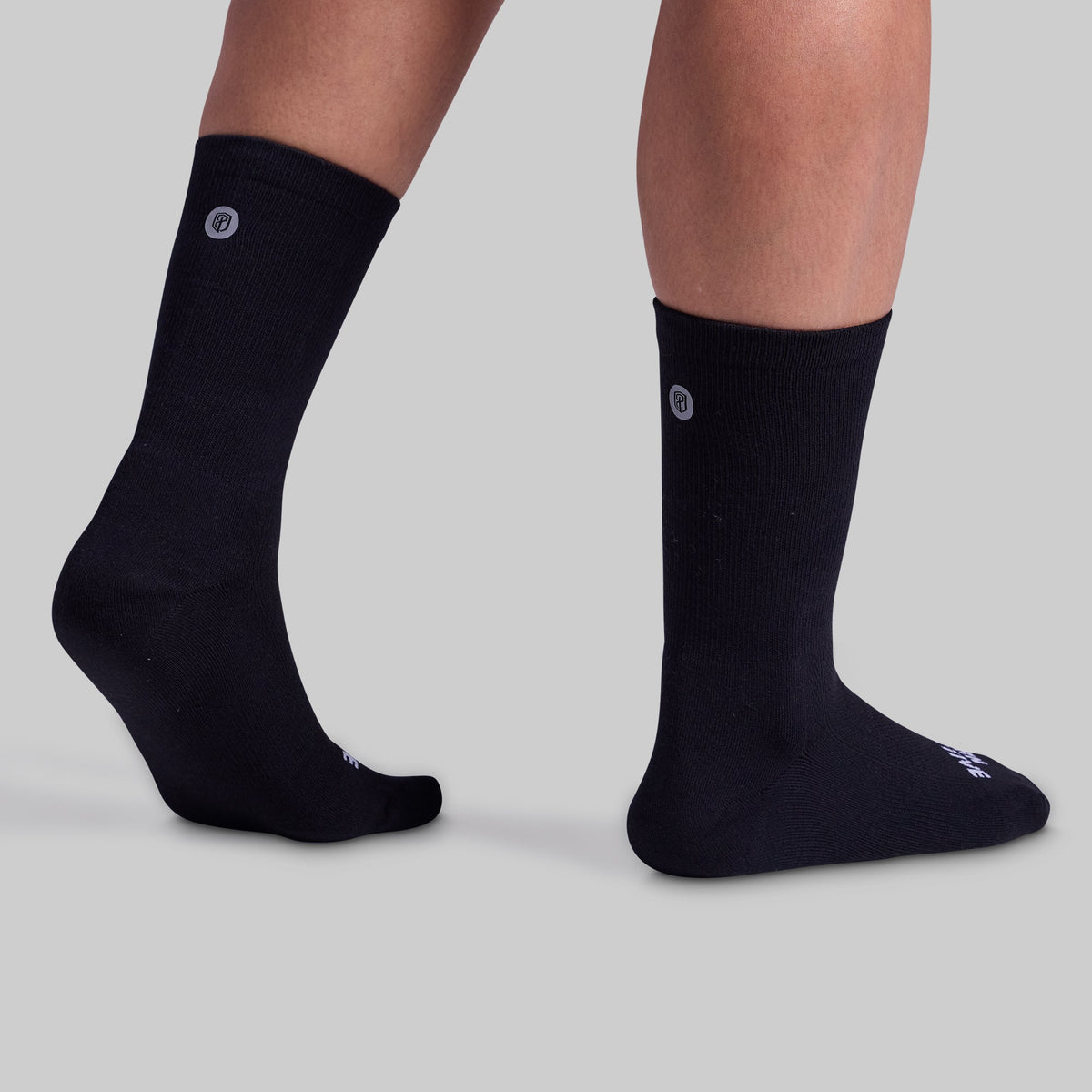 A pair of black performance crew socks with cushioned panels, displayed on a model's legs.