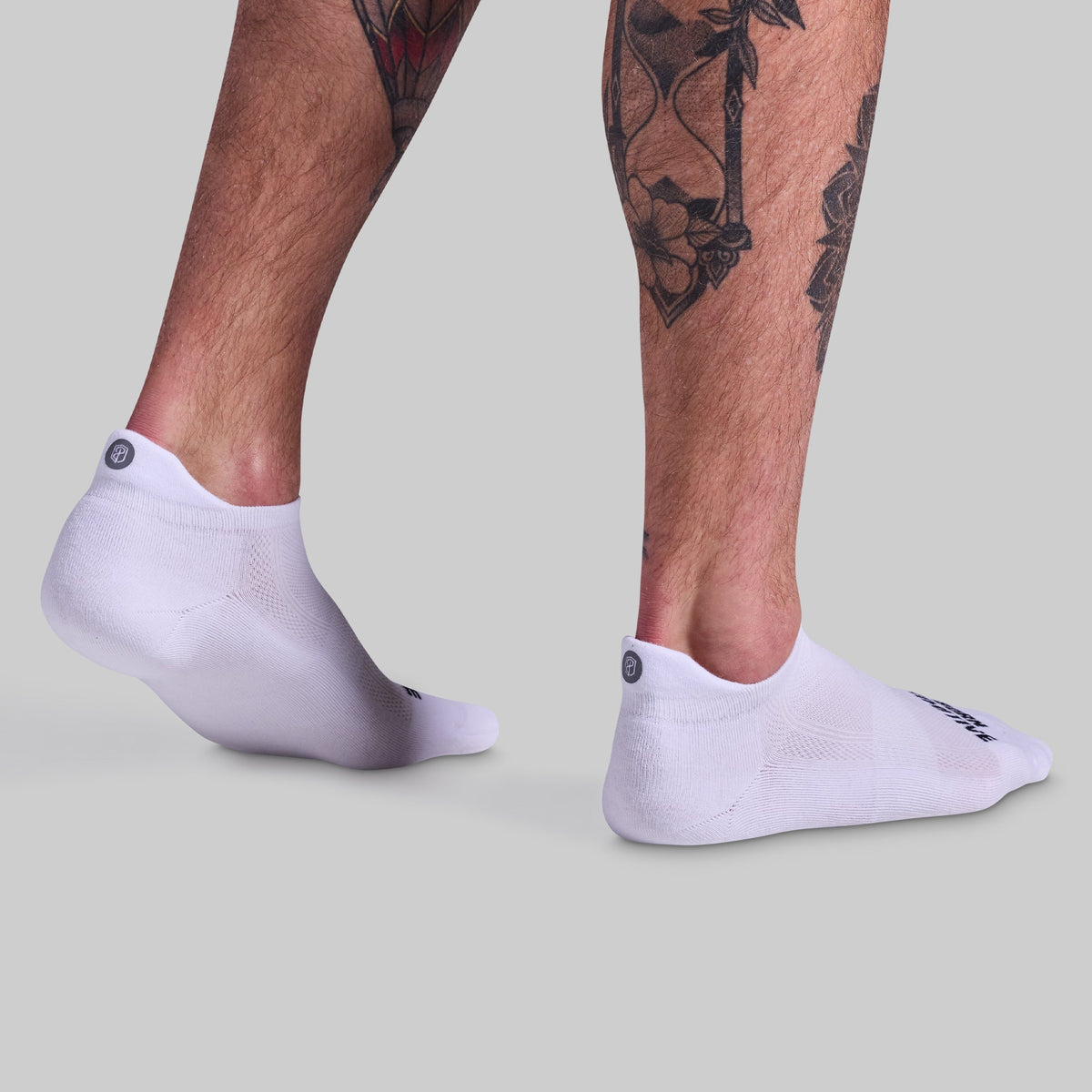 White socks worn with tattooed legs on a light gray background