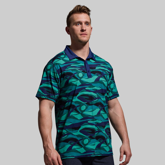 A man wearing a blue and green geometric patterned polo shirt with short sleeves and a collar.