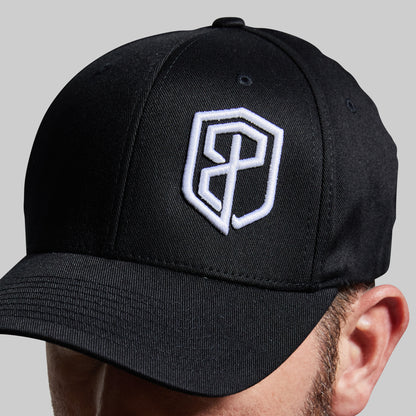 Black cap with a white logo worn by a person on a gray background
