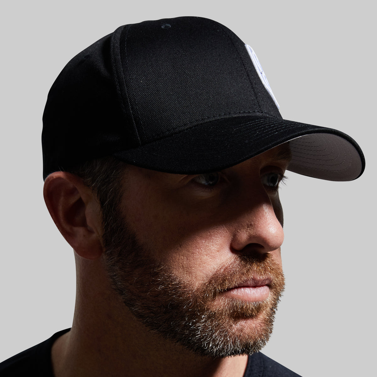 Man wearing a black cap against a gray background