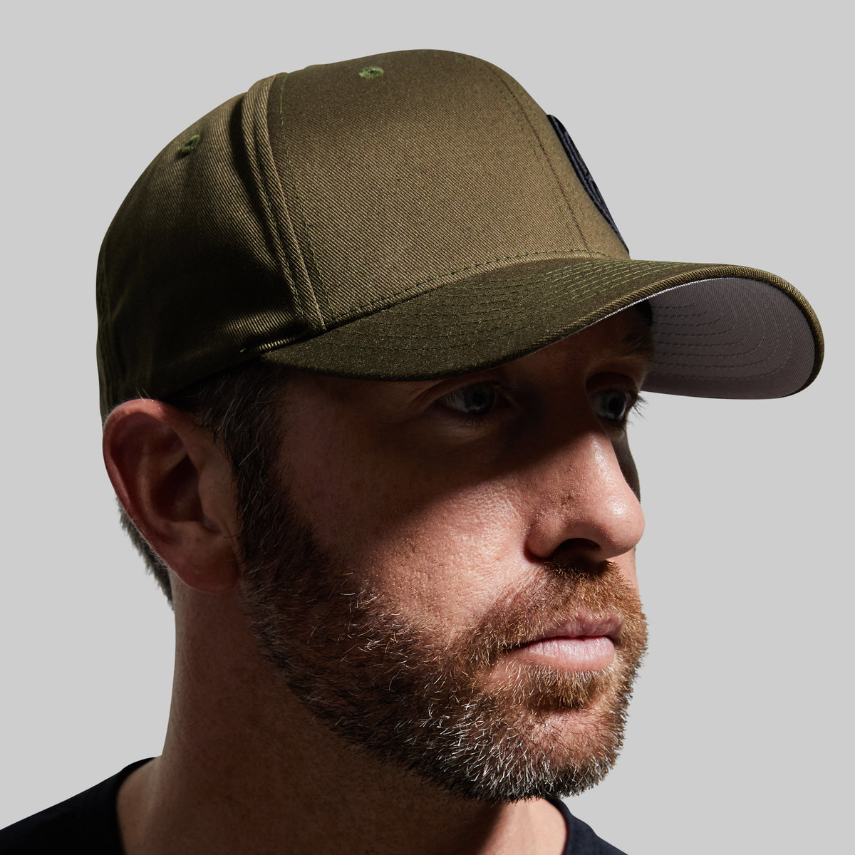 Man wearing a green cap against a gray background
