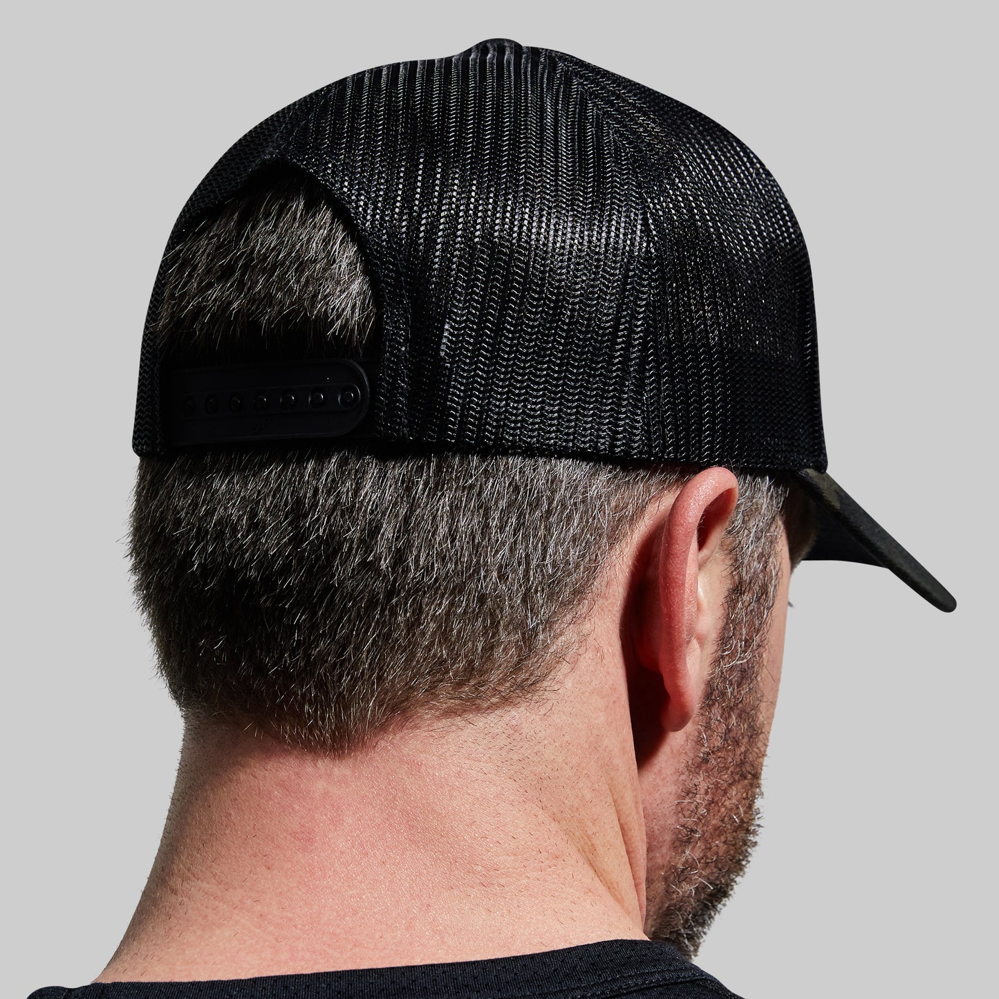 Back view of a man wearing a black trucker hat.