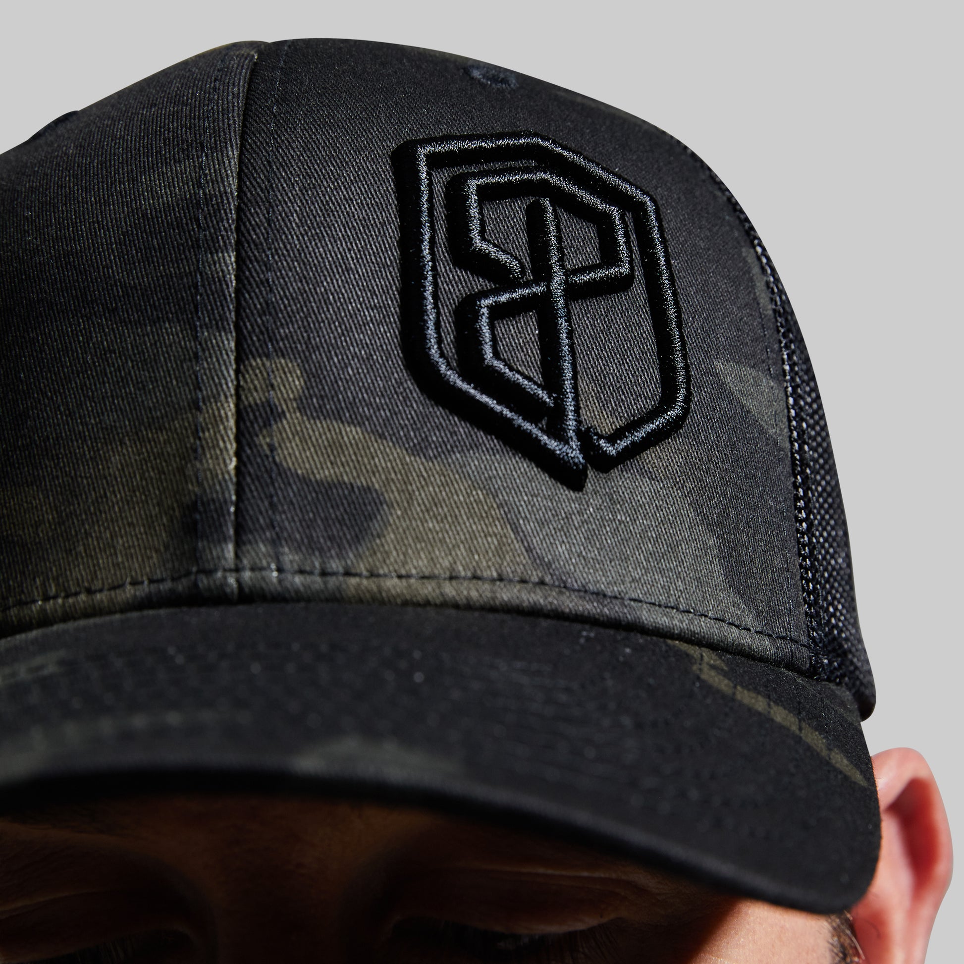 Close-up of logo on a camouflage hat.