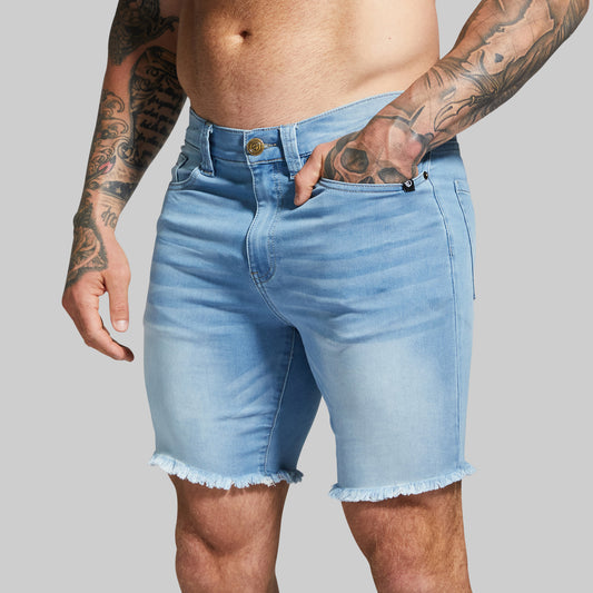 Person wearing light blue denim shorts with a gray background