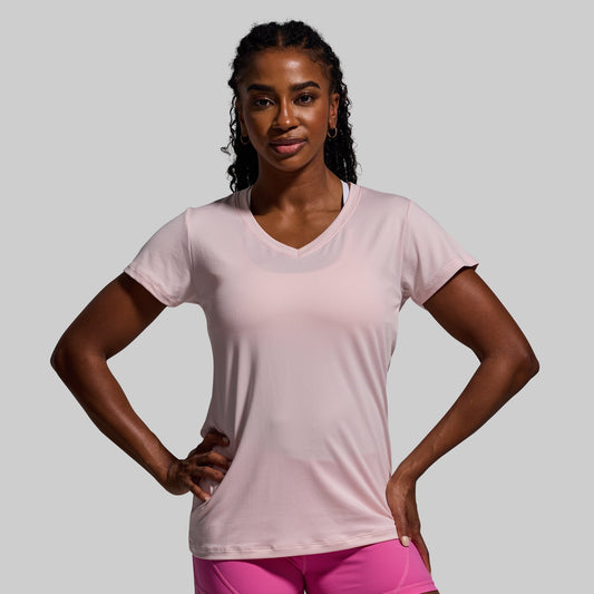 Woman wearing a light pink t-shirt and pink leggings against a gray background