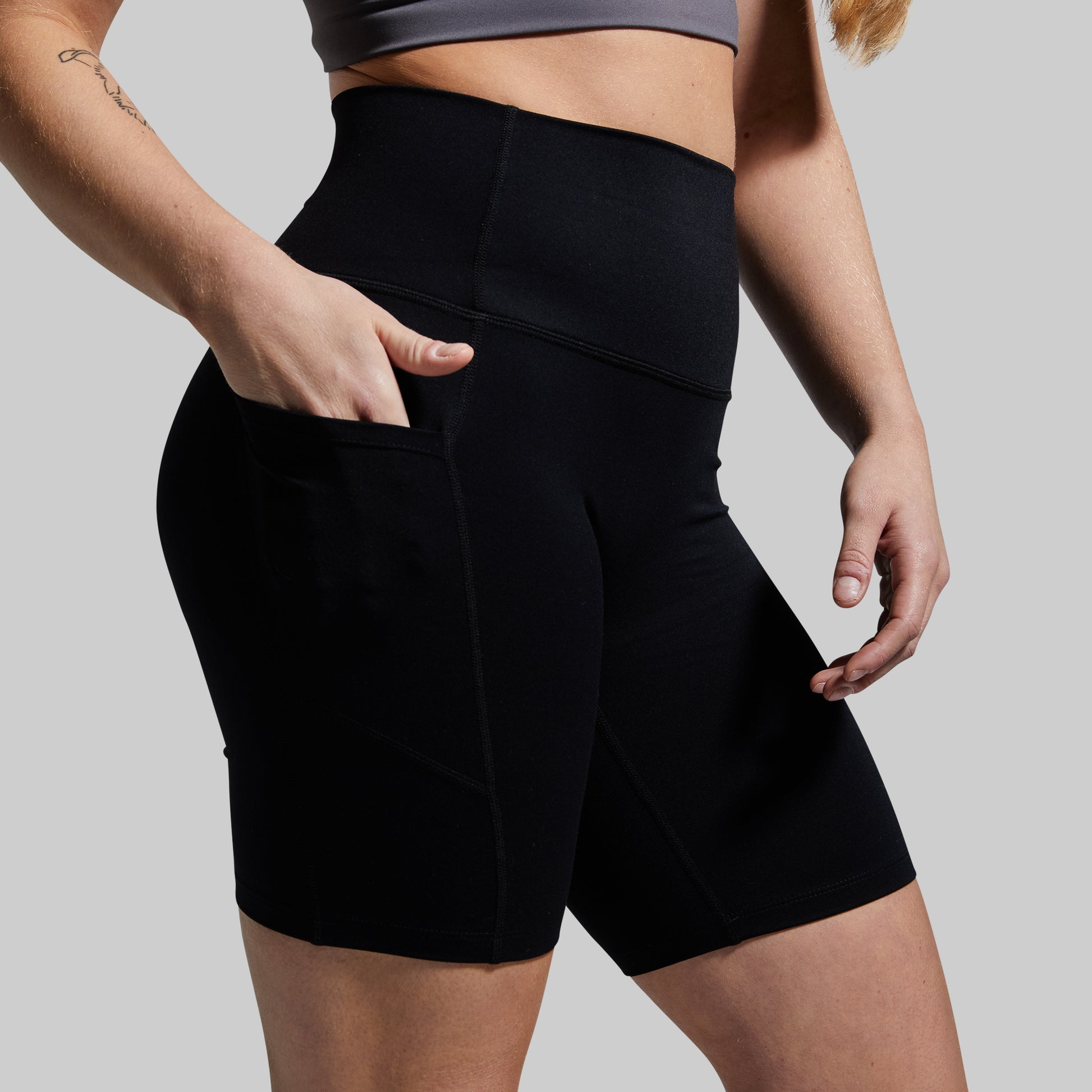 Person wearing black athletic shorts on a plain background
