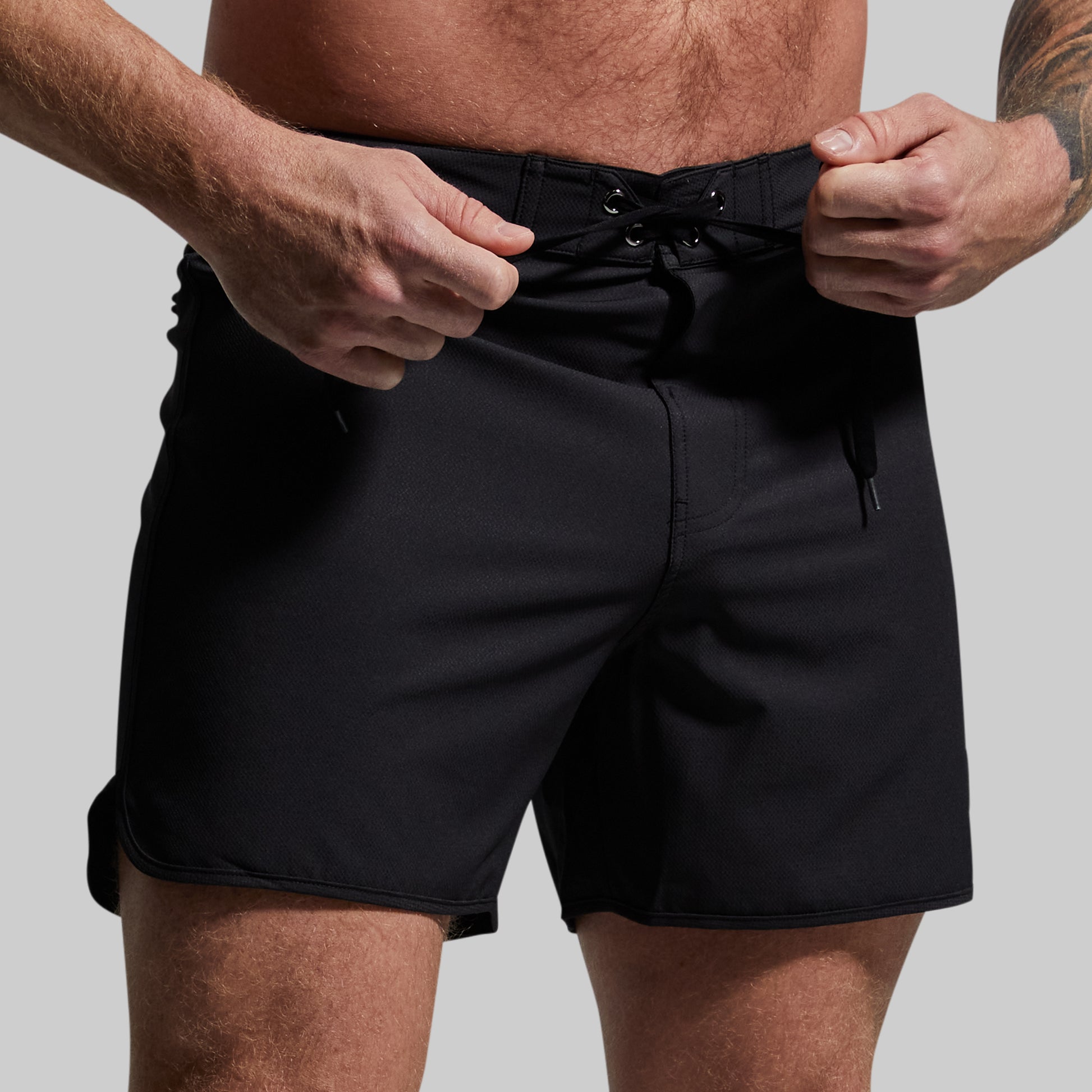 Person wearing black shorts with a plain background