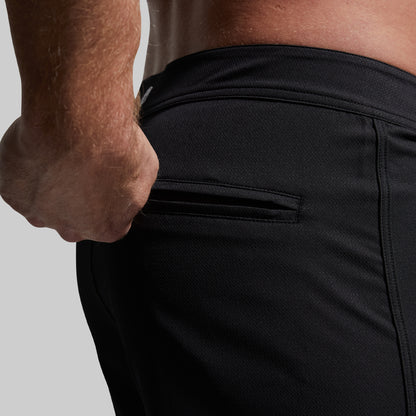 Person wearing black swim shorts with a focus on the waistband.