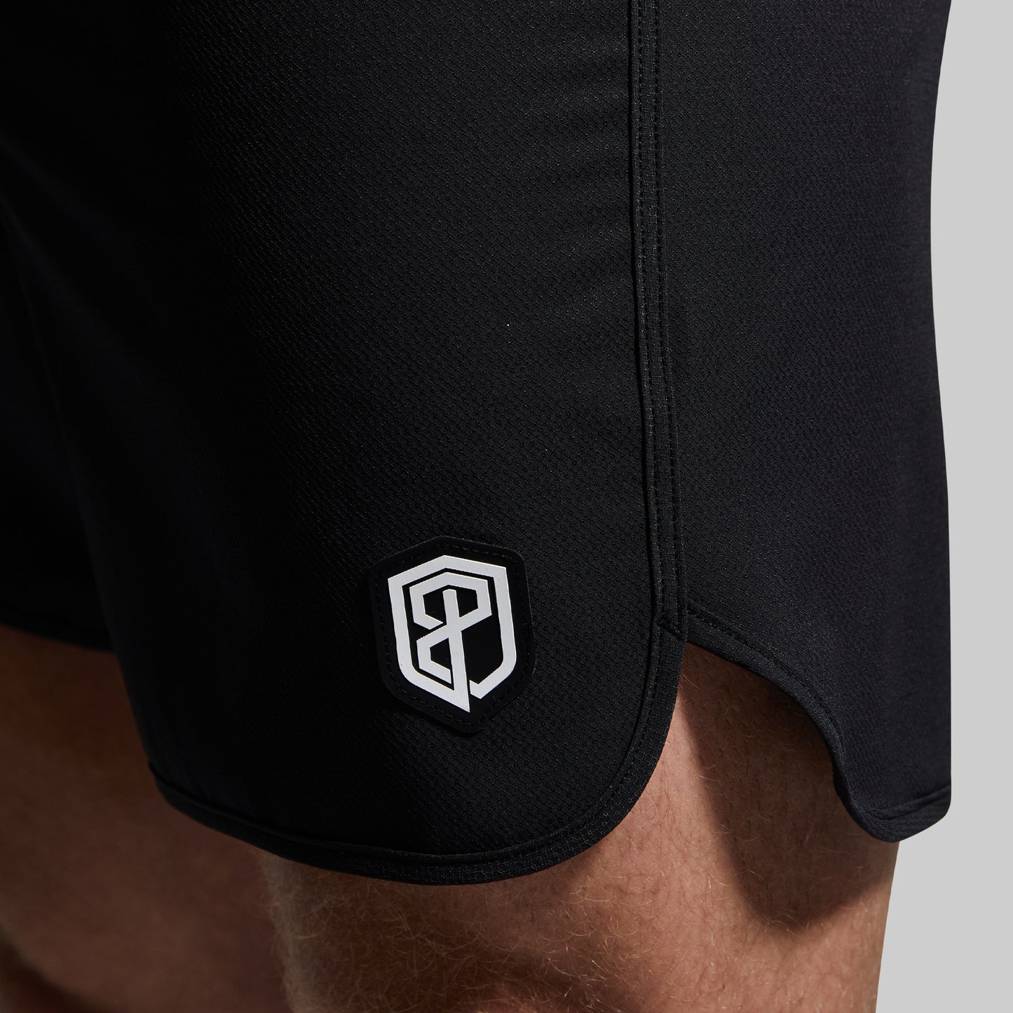 Black shorts with a logo on the side against a neutral background