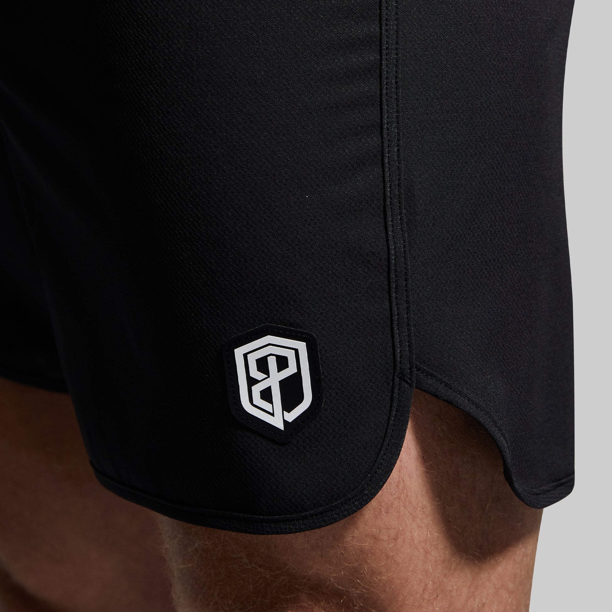 Black shorts with a logo on the side against a neutral background
