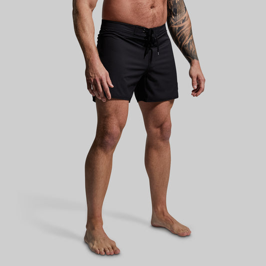 Person wearing black board shorts on a gray background