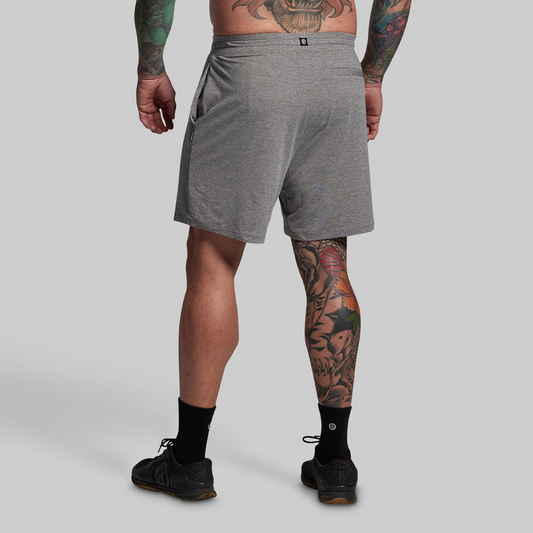 Person wearing gray shorts on a plain background