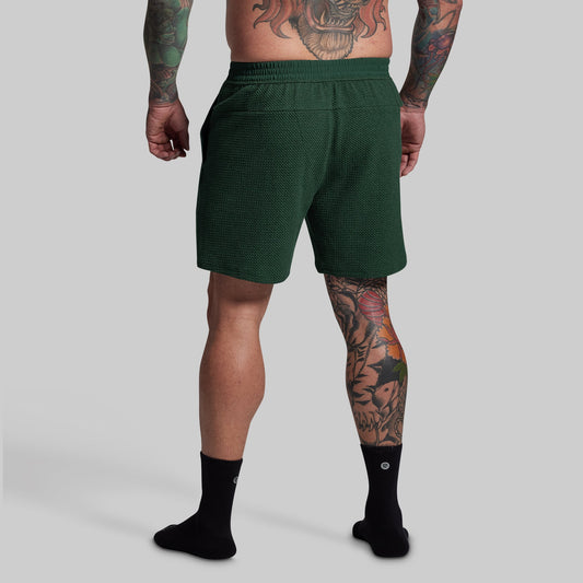 Person wearing green lounge shorts on a gray background
