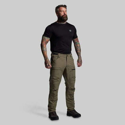 Man wearing a black t-shirt and green pants on a gray background