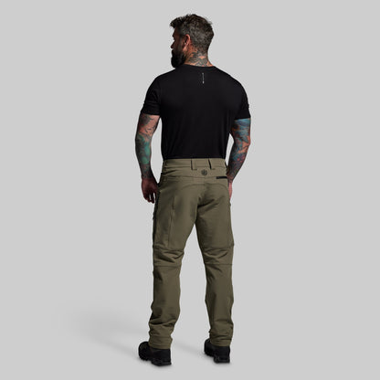 Man wearing olive green pants and a black t-shirt on a gray background
