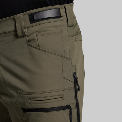 Close-up of olive green outdoor pants with zippers on a gray background
