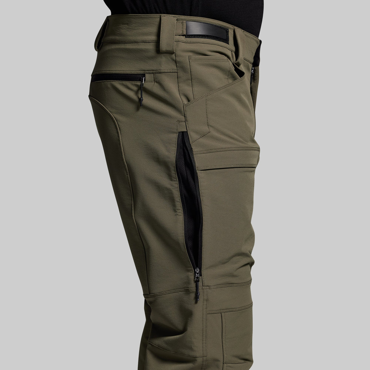 Olive green outdoor pants with multiple pockets on a gray background