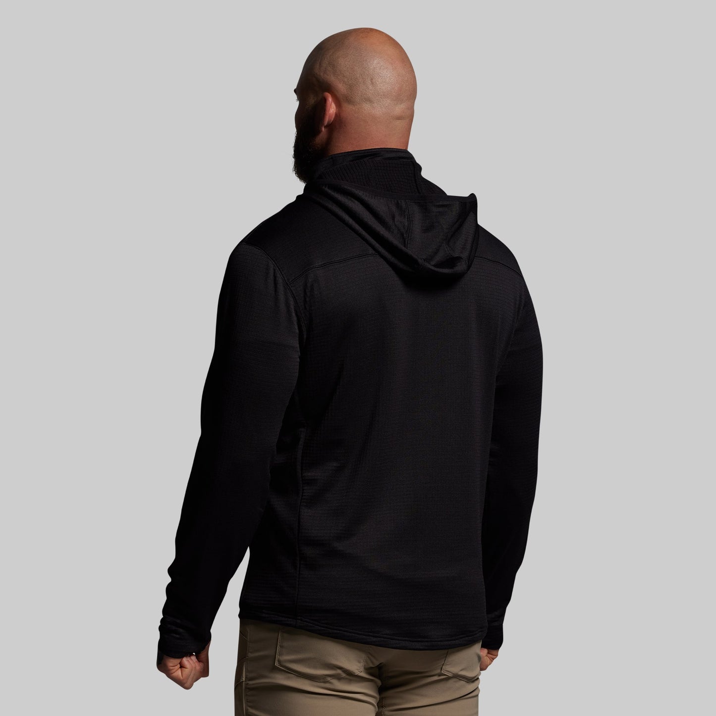 Man wearing a black hoodie from behind on a gray background