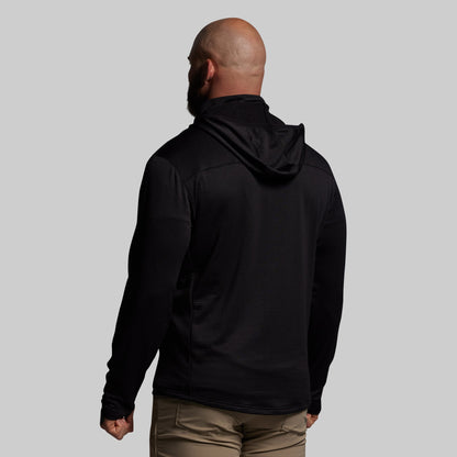 Man wearing a black hoodie from behind on a gray background