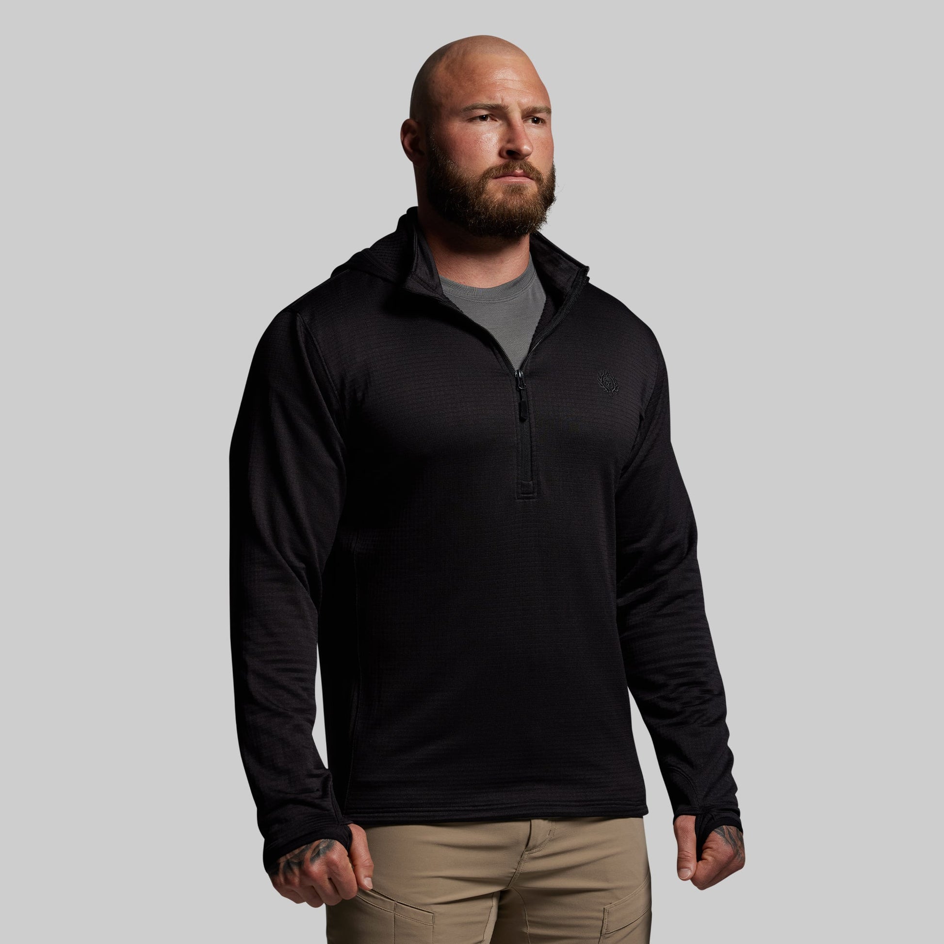 Man wearing a black quarter zip hoodie  on a gray background
