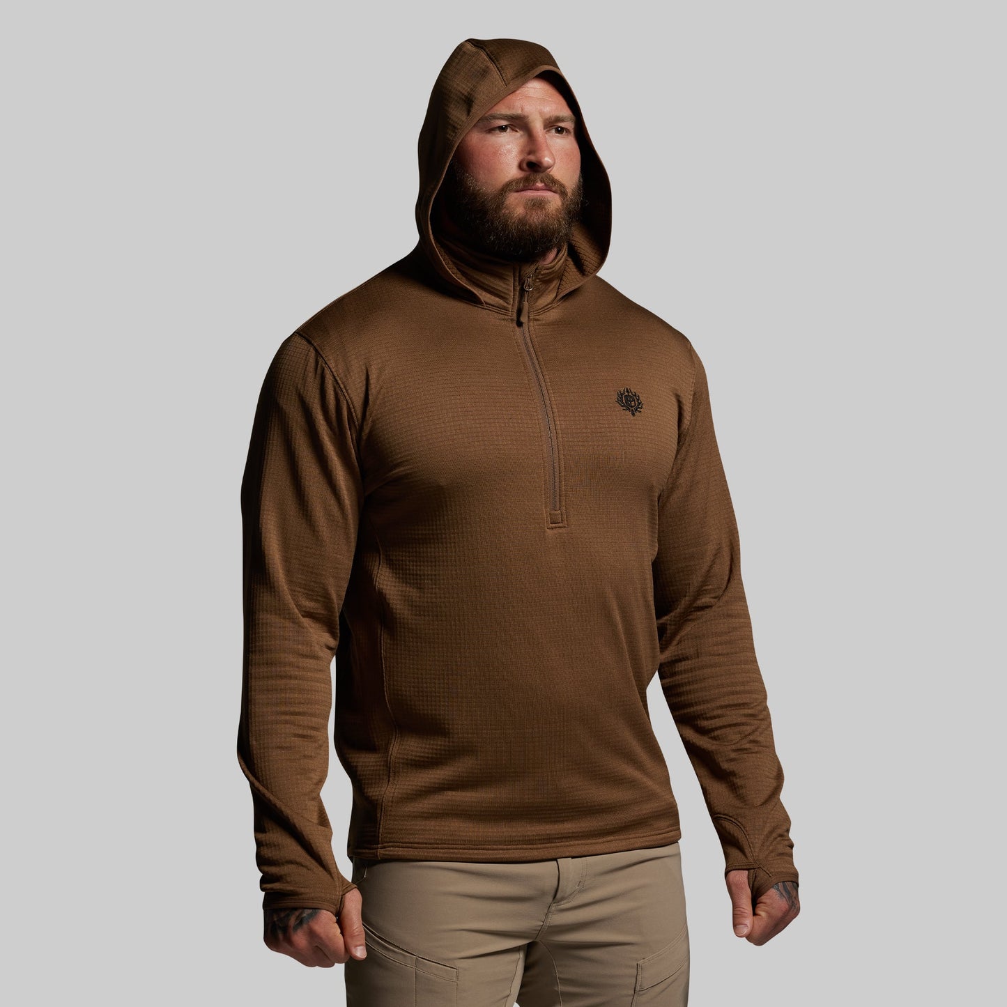 Man wearing a brown hoodie with a small logo on a gray background
