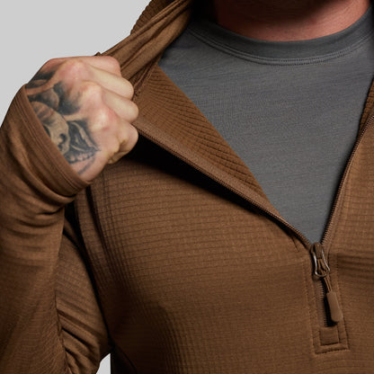Person wearing a brown hoodie with a gray shirt underneath, on a plain background