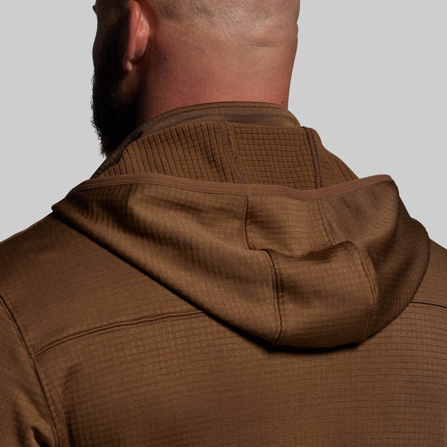 Brown textured hoodie worn by a person on a plain background