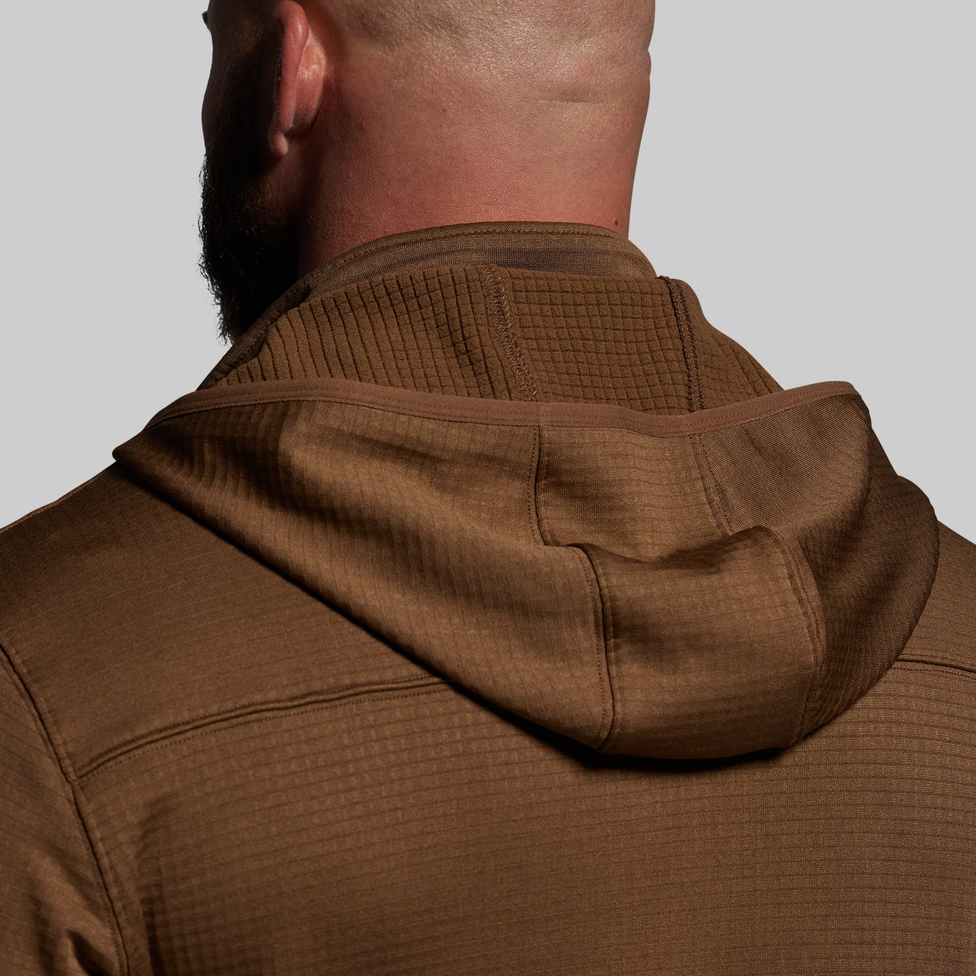 Brown textured hoodie worn by a person on a plain background
