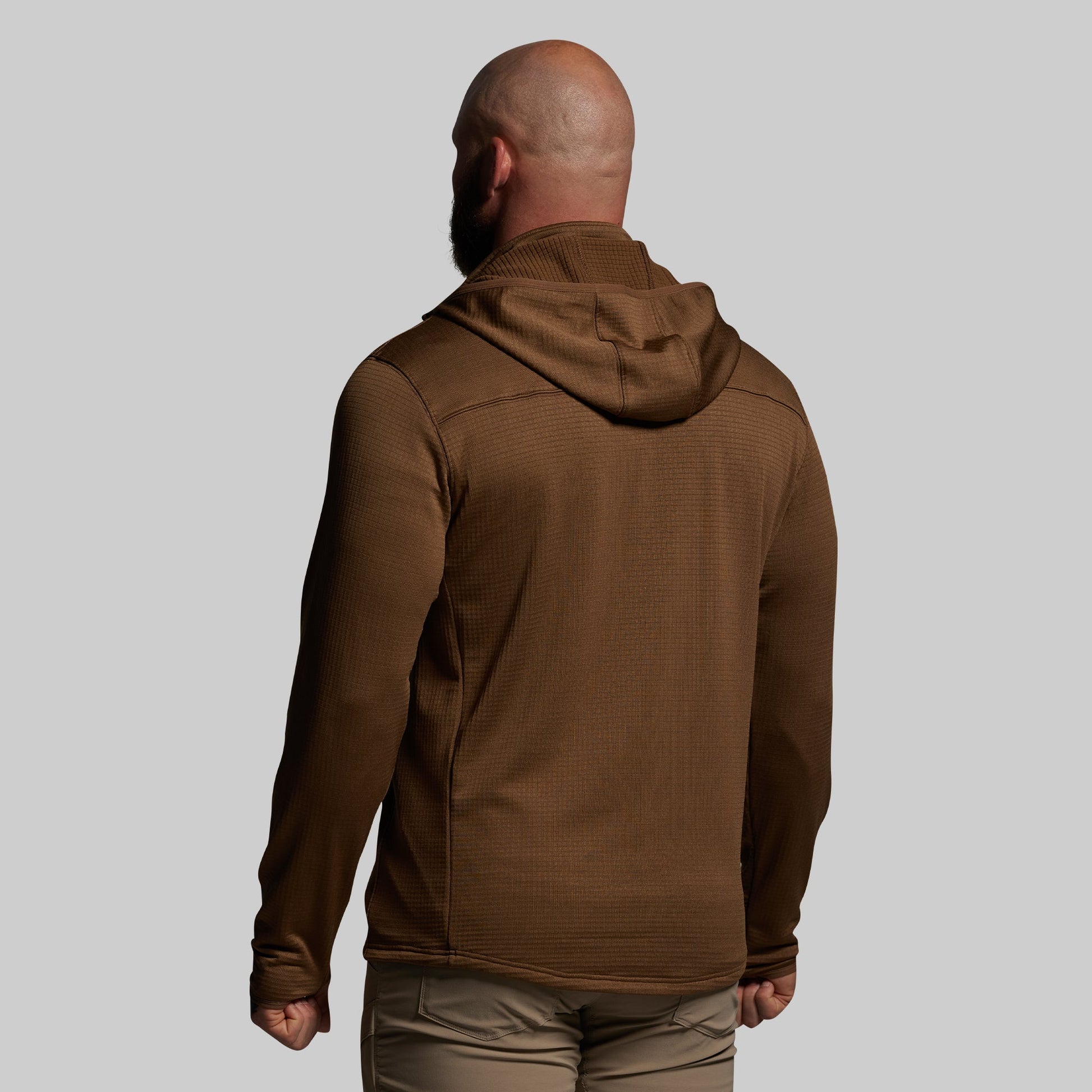 Man wearing a brown hoodie from behind on a gray background