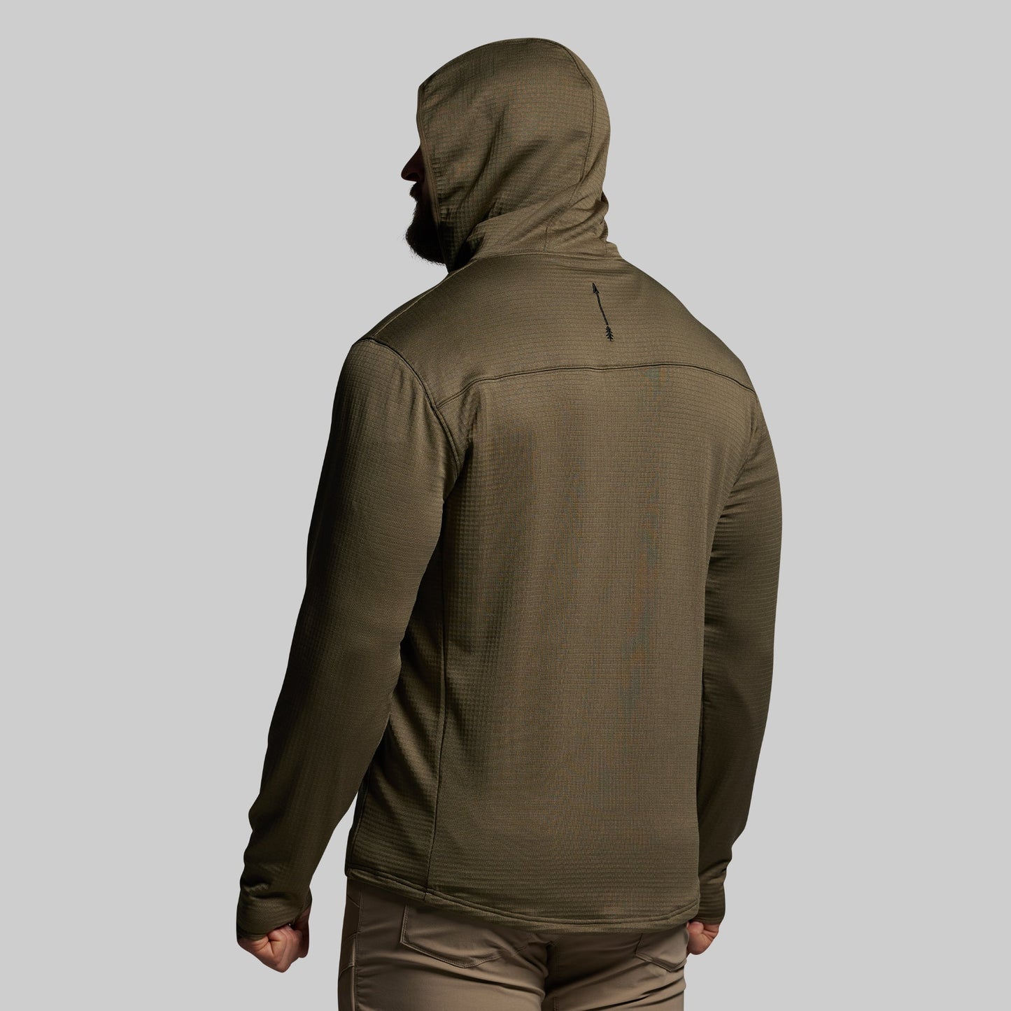 Person wearing a green hooded mid layer on a gray background